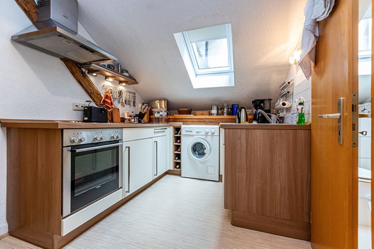 Küche mit Backofen, Waschmaschine und Küchenutensilien.